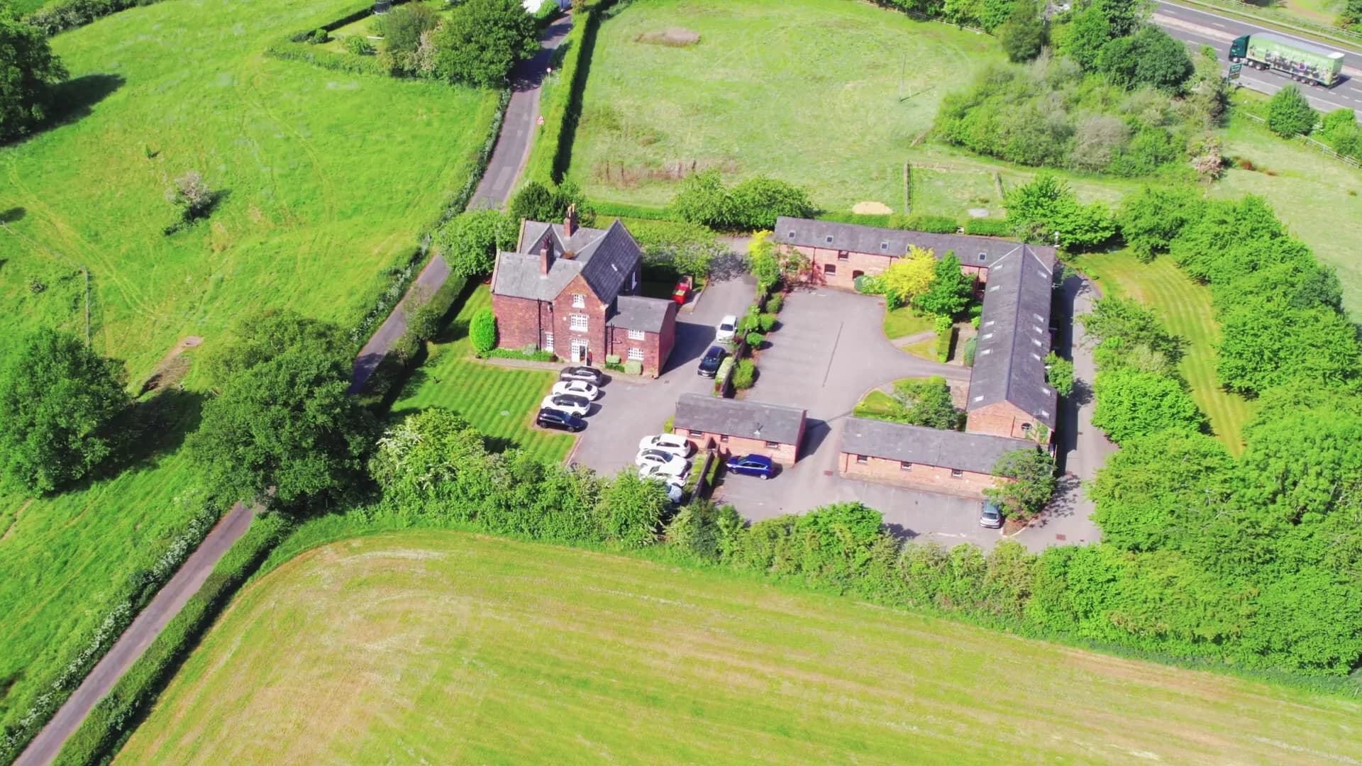 Cherry Tree House, its courtyard and parking, seen from the air among the Cheshire fields.
