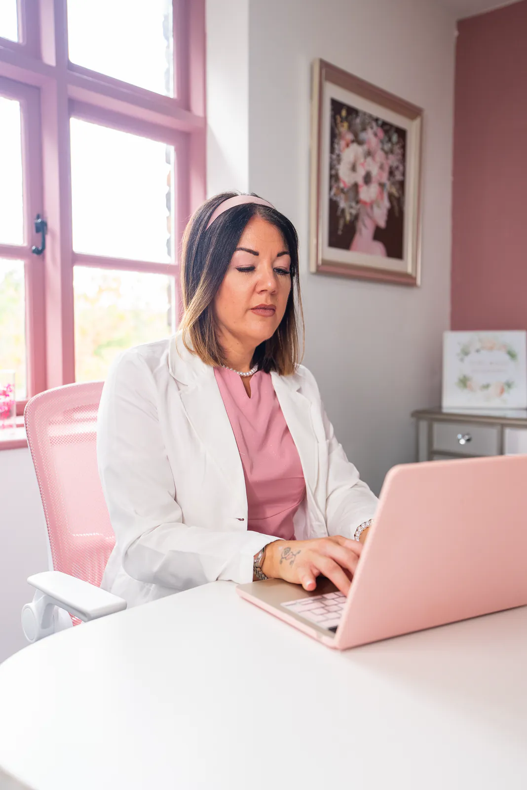 A House of GirlBoss team member working at a pink laptop in Cherry Tree House.