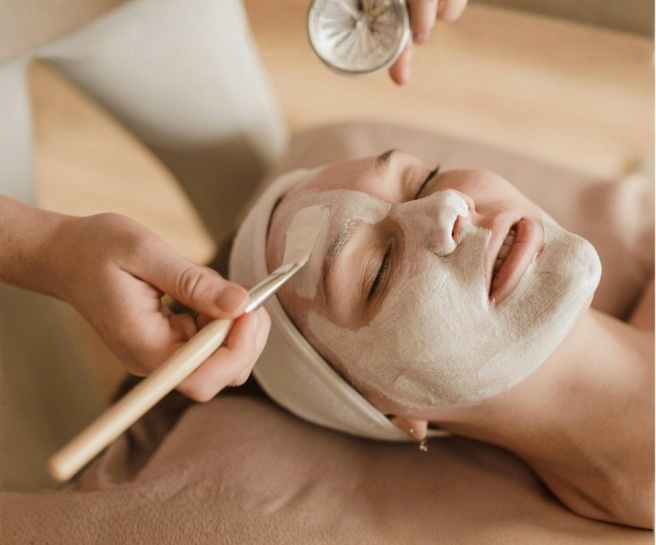 A clay mask being brushed onto a client's face during a facial.
